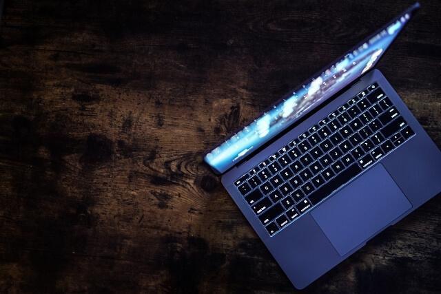 木目デスクに開いたノートパソコン